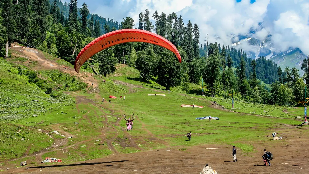 Paraglider above snow-covered peaks near Solang Valley, Manali